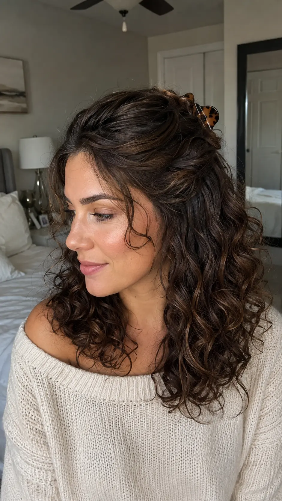 Half-up shoulder length curly hairstyle with claw clip