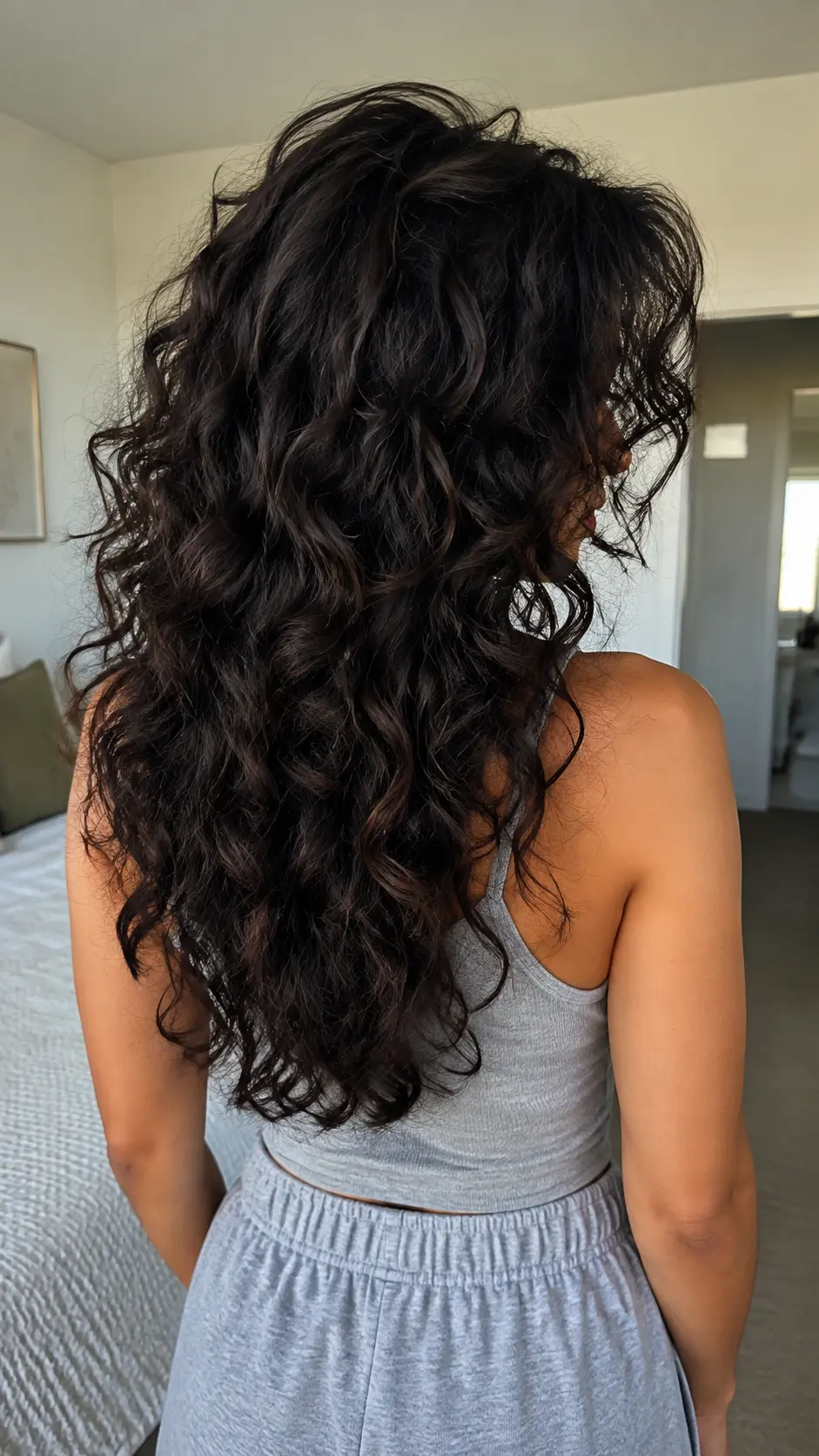 Voluminous dark brunette curly butterfly haircut with thick curls